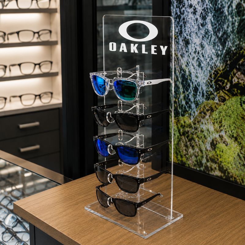 מעמד פרספקס שקוף למשקפי שמש ממותג Oakley על דלפק בחנות אופטיקה מודרנית מעמד פרספקס שקוף למשקפי שמש ממותג Oakley על דלפק בחנות אופטיקה מודרנית